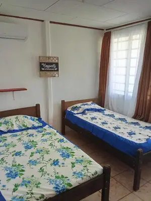 a room with two beds and a sign on the wall at Apartamentos y Cabinas Geckos in Sardinal