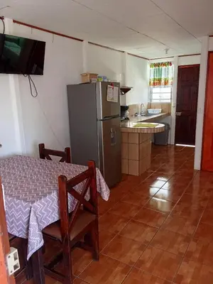 a kitchen with a table and a refrigerator at Apartamentos y Cabinas Geckos in Sardinal