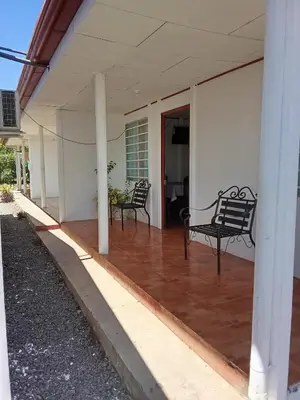 a porch with two black chairs on a house at Apartamentos y Cabinas Geckos in Sardinal