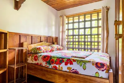 a bedroom with a bed with a floral comforter and a window at Cabinas Mi Sol in Uvita