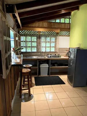 a kitchen with a refrigerator and a table and a stool at Cabinas Mi Sol in Uvita