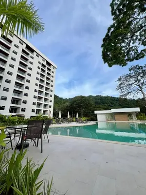 a swimming pool with two chairs and a building at Entire home with Private Pool - Coralita in Jaco, gated community, walking distance to Jaco Beach in Jacó