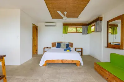 a bedroom with a bed and a green couch at Ocean View Bungalows in Pital