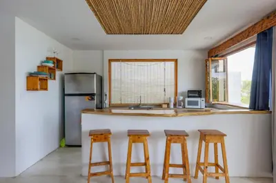 a kitchen with a counter with three bar stools at Ocean View Bungalows in Pital
