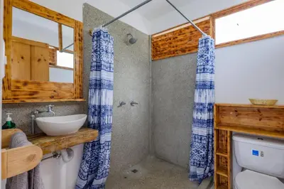 a bathroom with a blue and white shower curtain at Ocean View Bungalows in Pital