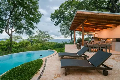 a villa with a swimming pool and patio furniture at villa colibri in Nicoya