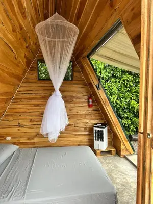 a bedroom with a bed in a wooden house at Eco Glamping Verde, Bahia Gigante in Puntarenas