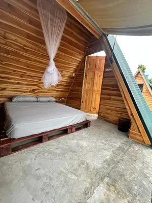 a bedroom with a bed in a wooden house at Eco Glamping Verde, Bahia Gigante in Puntarenas
