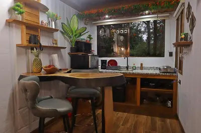 a kitchen with a bar with stools and a counter at El santuario - Cabin by a River in Fortuna