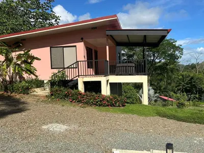 a pink house with a balcony and flowers at Villas Carari in Hatillo