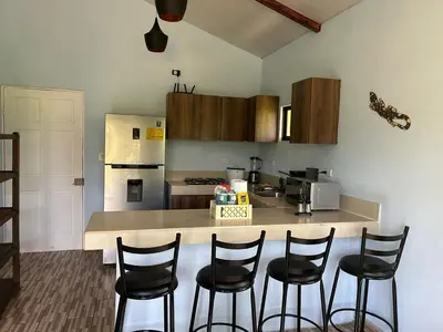 a kitchen with a counter with chairs around it at Villas Carari 2 in Savegre