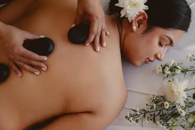 a woman laying on a bed with spa balls on her stomach at Kalma Suite & Spa in Monteverde Costa Rica