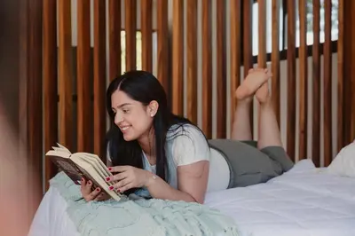 a woman laying on a bed reading a book at Kalma Suite & Spa in Monteverde Costa Rica