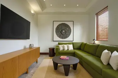 a living room with a green couch and a flat screen tv at Nekajui Peninsula Papagayo, a Ritz-Carlton Reserve Residence in Papagayo, Guanacaste