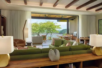 a living room with a green couch and a table at Nekajui Peninsula Papagayo, a Ritz-Carlton Reserve Residence in Papagayo, Guanacaste