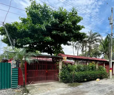 a red gate in front of a house with a tree at Apartamento el Almendro in Liberia