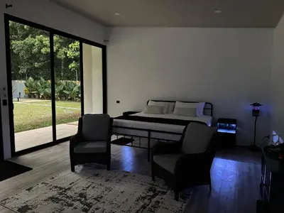 a bedroom with a bed and two chairs at Seven Paradise - Your personal rainforest in Fortuna