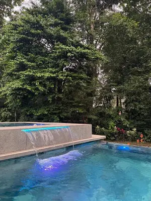 a swimming pool with a fountain in a yard at Seven Paradise - Your personal rainforest in Fortuna