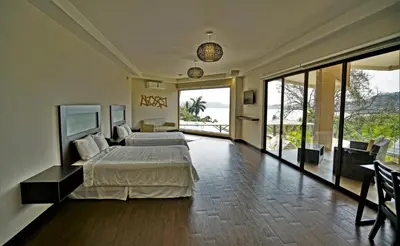 a bedroom with a bed and a view of the ocean at Nammbú Beach Front Bungalows in Sámara