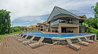 a villa with a swimming pool and lounge chairs at Nammbú Beach Front Bungalows in Sámara