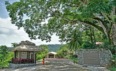 a building with a sign next to a road at Nammbú Beach Front Bungalows in Sámara