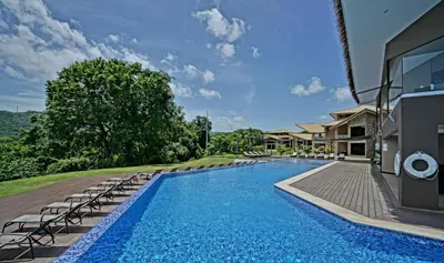 a swimming pool with lounge chairs next to a house at Nammbú Beach Front Bungalows in Sámara
