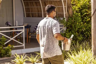 a man is holding a drink in a bucket at Les Voiles Blanches in Tamarindo