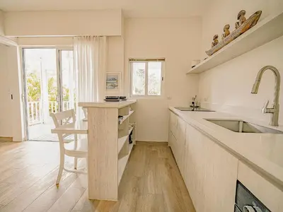 a kitchen with a sink and a counter with a table at Les Voiles Blanches in Tamarindo