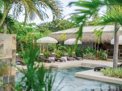 a pool with chairs and umbrellas in a resort at Les Voiles Blanches in Tamarindo