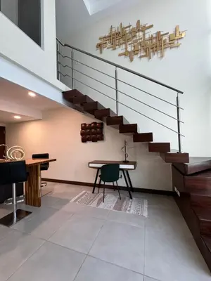a room with a staircase with a table and a bench at Penthouse in San Jose Costa Rica in San José