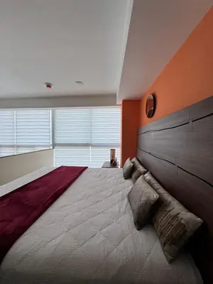 a bedroom with a large bed with orange walls at Penthouse in San Jose Costa Rica in San José