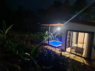 a small house with a swimming pool at night at Pantala Villa in Fortuna