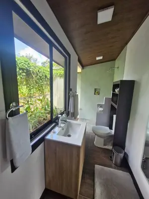 a bathroom with a sink and a toilet and a window at Pantala Villa in Fortuna
