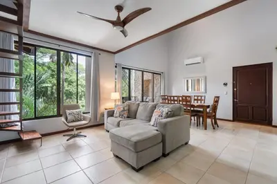 a living room with a couch and a table at Modern Island-Themed Condo with Floor-to-Ceiling Windows & Garden and Pool Views Within Walking Distance of the Beach in Coco