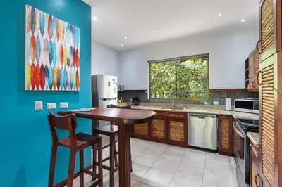 a kitchen with a wooden table and a blue wall at Modern Island-Themed Condo with Floor-to-Ceiling Windows & Garden and Pool Views Within Walking Distance of the Beach in Coco