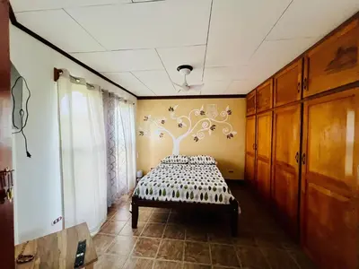 a bedroom with a bed with a tree on the wall at Casa Las Brisas del Miravalles in Bagaces
