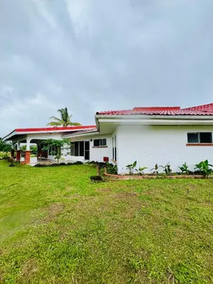 a white house with a red roof and a yard at Casa Las Brisas del Miravalles in Bagaces