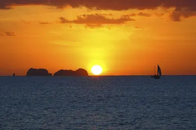 a sail boat in the ocean at sunset at Twin Dolphins 2A in Playa Flamingo