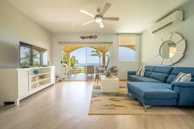 a living room with a blue couch and a ceiling fan at Twin Dolphins 2A in Playa Flamingo