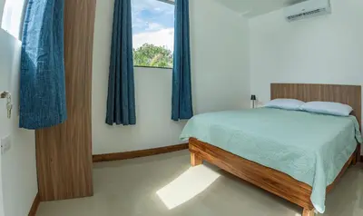 a bedroom with a bed with blue curtains and a window at Sweet Dreams the Arenal in Fortuna