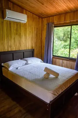 a bed in a wooden room with a window at La jungla ecolodge in San Juan