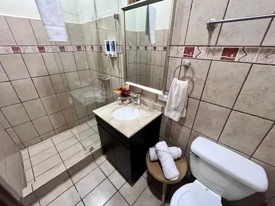 a bathroom with a white toilet and a sink at Hotel Villas de la Colina in Atenas