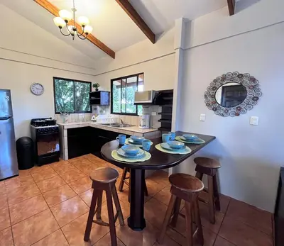 a kitchen with a table and stools in a room at Hotel Villas de la Colina in Atenas