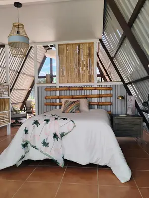 a bedroom with a bed with a white comforter at A-frame cabin in Palma