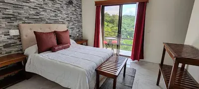 a bedroom with a bed and a large window at Monteverde Coati & Sloth Studios Apartaments Hotel in Monteverde Costa Rica
