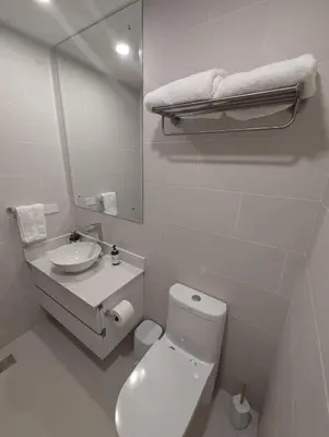 a bathroom with a toilet and a sink and a mirror at Stylish 2 bed and 2 bath condo with mountain and pool view in Jacó in Jacó