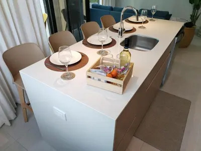 a kitchen island with wine glasses and a sink at Stylish 2 bed and 2 bath condo with mountain and pool view in Jacó in Jacó