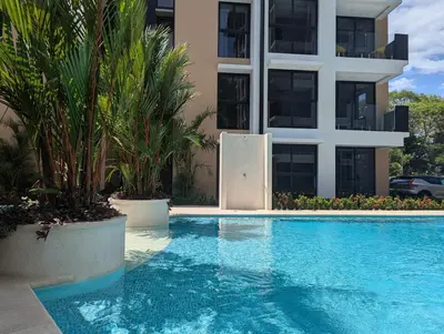 a swimming pool in front of a building at Stylish 2 bed and 2 bath condo with mountain and pool view in Jacó in Jacó