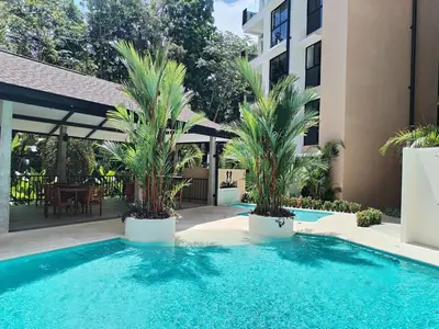 a swimming pool with two palm trees next to a building at Stylish 2 bed and 2 bath condo with mountain and pool view in Jacó in Jacó