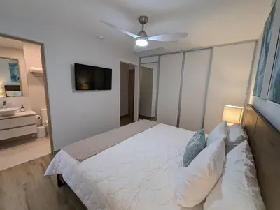 a bedroom with a white bed and a ceiling fan at Stylish 2 bed and 2 bath condo with mountain and pool view in Jacó in Jacó